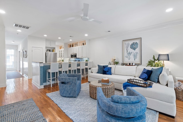 living area with ceiling fan, visible vents, baseboards, light wood finished floors, and recessed lighting