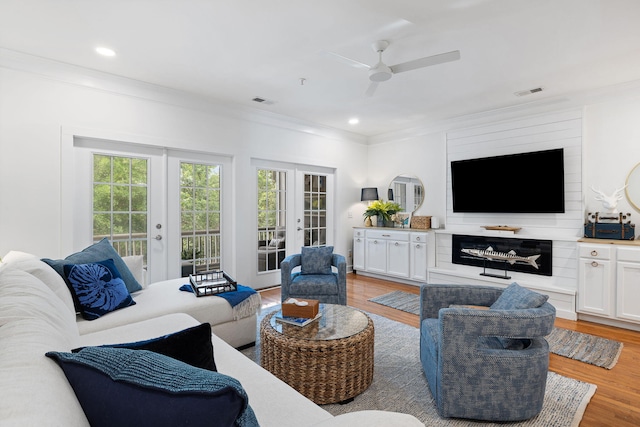 living area featuring crown molding, visible vents, french doors, a ceiling fan, and light wood-style flooring