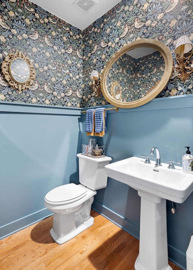 bathroom with baseboards, visible vents, and wallpapered walls