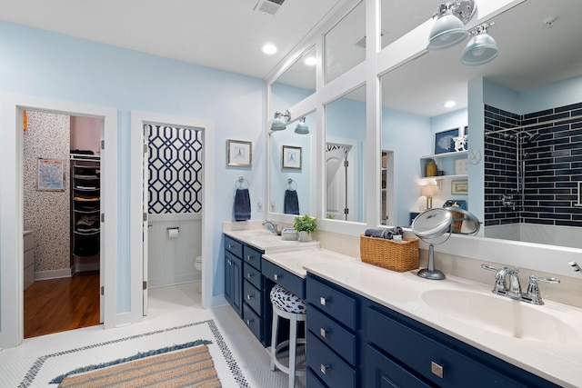 full bathroom featuring visible vents, double vanity, toilet, a spacious closet, and a sink
