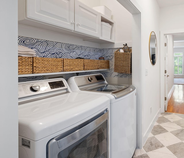 clothes washing area featuring baseboards, cabinet space, and washing machine and clothes dryer
