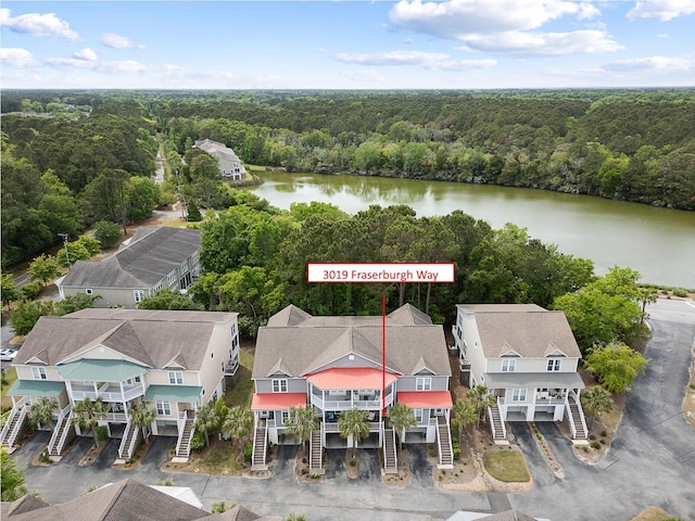 birds eye view of property with a water view and a wooded view