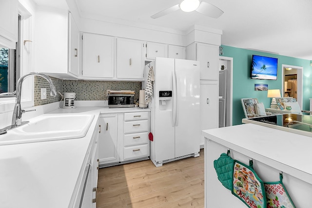 kitchen with sink, white refrigerator with ice dispenser, white cabinetry, ceiling fan, and light hardwood / wood-style flooring