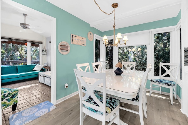 dining area featuring wood-type flooring and ceiling fan with notable chandelier