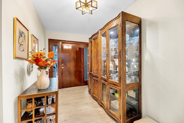 doorway with light hardwood / wood-style floors and a textured ceiling