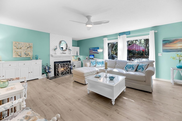 living room featuring light hardwood / wood-style flooring, a fireplace, and ceiling fan