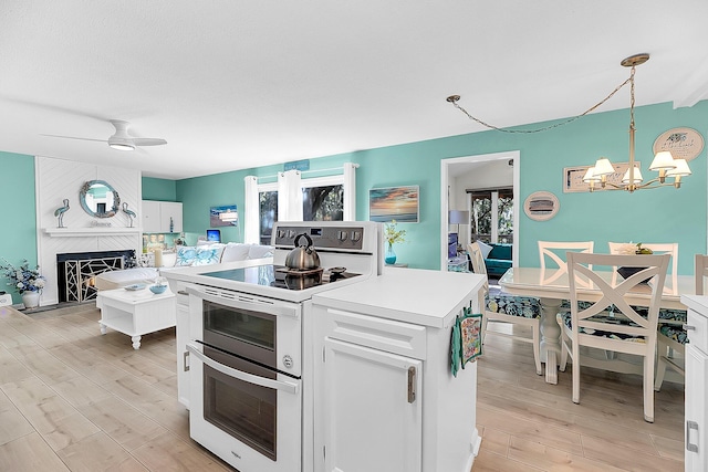 kitchen with light hardwood / wood-style flooring, white cabinets, decorative light fixtures, and electric range