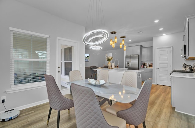 dining space with a notable chandelier, sink, and light wood-type flooring