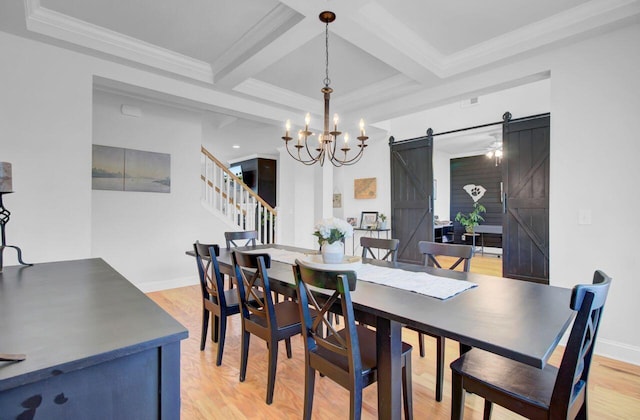 dining area with beamed ceiling, a barn door, light hardwood / wood-style floors, and coffered ceiling