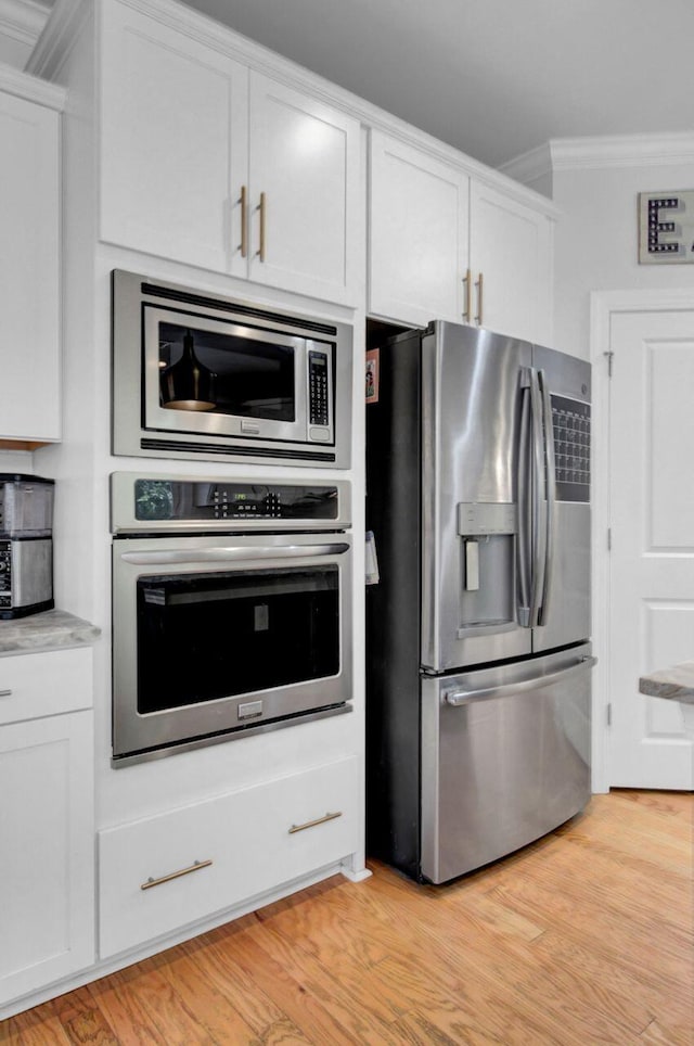 kitchen with white cabinetry, crown molding, light wood-type flooring, and appliances with stainless steel finishes