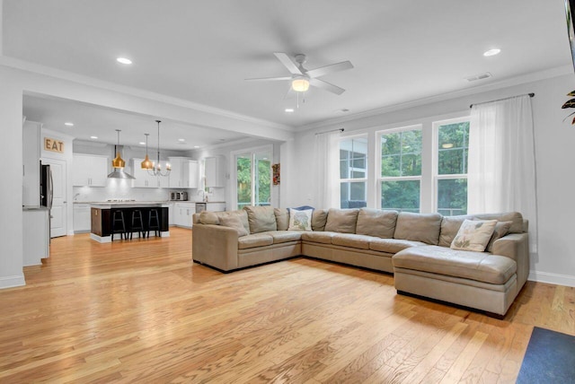 living room with light hardwood / wood-style floors, ceiling fan, and crown molding