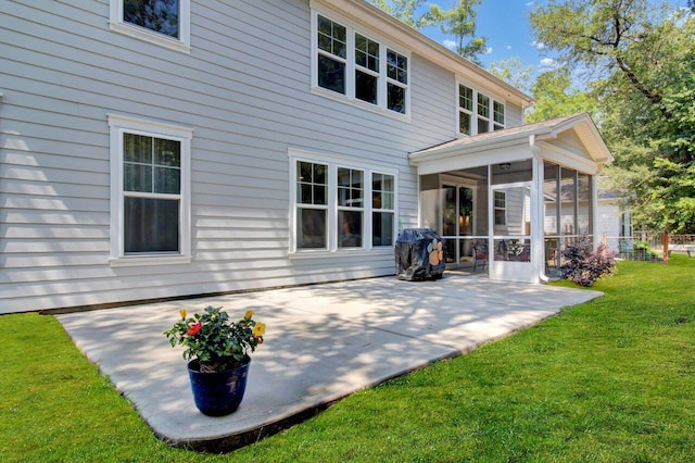 back of property with a sunroom, a patio area, and a lawn