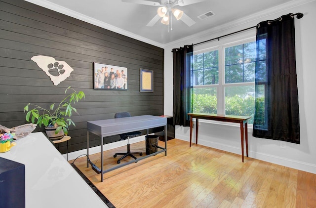 office space with ceiling fan, wood-type flooring, ornamental molding, and wooden walls