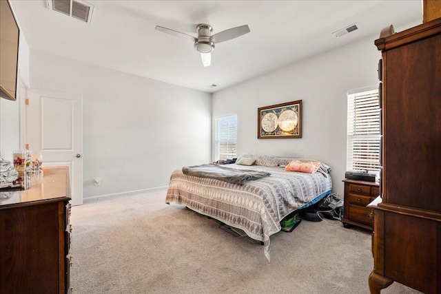 bedroom featuring ceiling fan, light carpet, and multiple windows