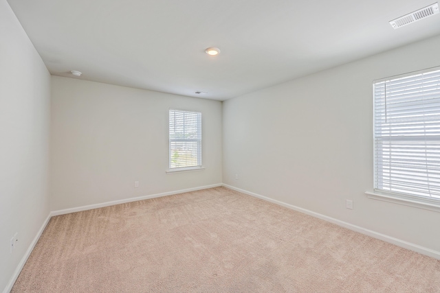 carpeted spare room with healthy amount of natural light, baseboards, and a smoke detector