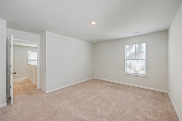 spare room featuring light carpet and baseboards