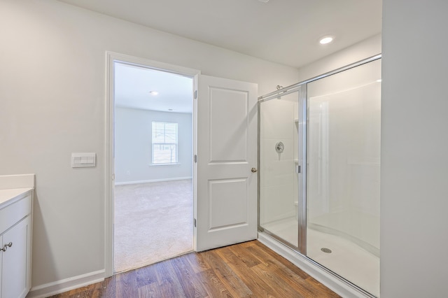 full bathroom featuring a stall shower, vanity, wood finished floors, and baseboards