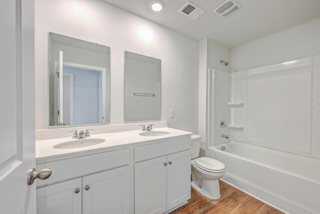 full bathroom featuring toilet, wood finished floors, double vanity, and shower / tub combination