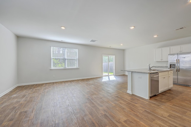 kitchen featuring appliances with stainless steel finishes, wood finished floors, open floor plan, white cabinetry, and recessed lighting