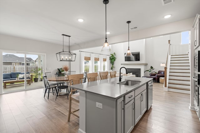 kitchen with a fireplace, open floor plan, gray cabinets, a sink, and appliances with stainless steel finishes