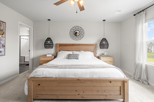 bedroom with visible vents, light carpet, baseboards, ceiling fan, and ensuite bath