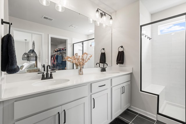 bathroom featuring a sink, a shower stall, double vanity, and visible vents