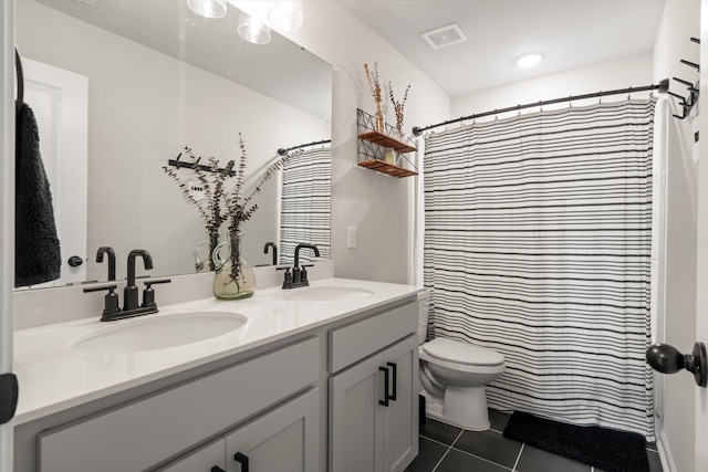 bathroom featuring a sink, tile patterned floors, toilet, and double vanity