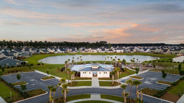 aerial view at dusk featuring a water view and a residential view