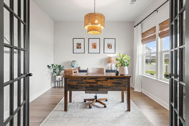 office space featuring baseboards, visible vents, wood finished floors, and a chandelier
