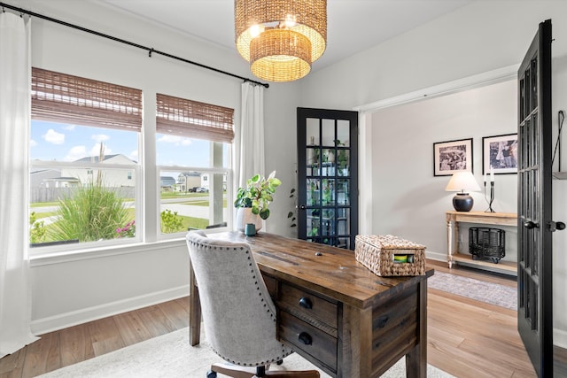 home office featuring baseboards, wood finished floors, and a chandelier