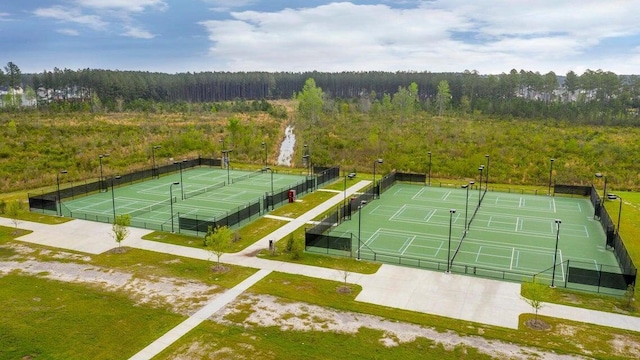 view of sport court featuring a forest view and fence