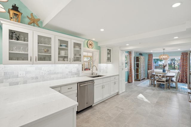 kitchen with stainless steel dishwasher, sink, hanging light fixtures, white cabinetry, and backsplash