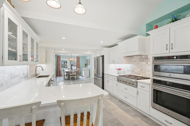 kitchen with lofted ceiling, sink, stainless steel appliances, a kitchen breakfast bar, and decorative backsplash