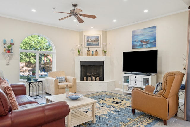 living room with ornamental molding, a fireplace, ceiling fan, and light tile patterned floors