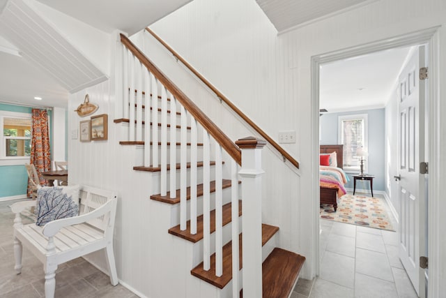 staircase featuring wood walls and tile patterned flooring