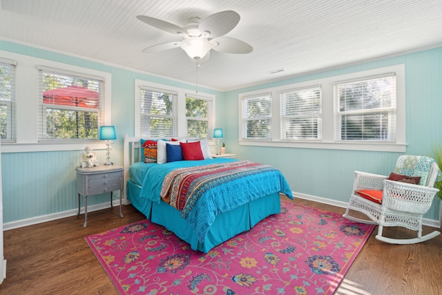 bedroom featuring dark wood-type flooring, wooden walls, and ceiling fan