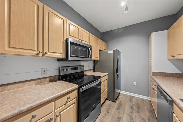 kitchen with light brown cabinetry, stainless steel appliances, and light hardwood / wood-style flooring