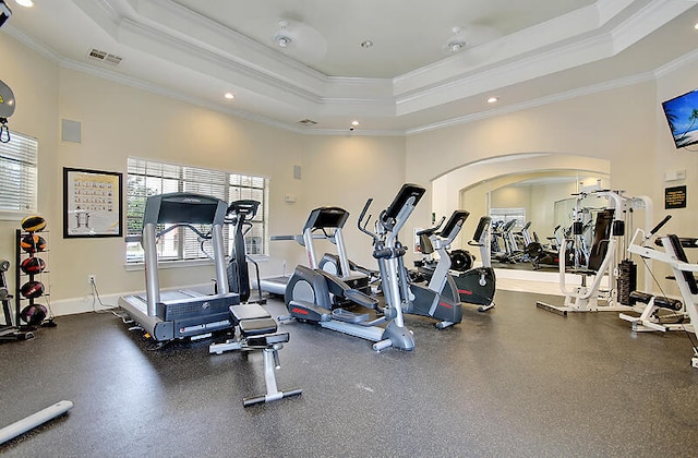 workout area with a tray ceiling and crown molding