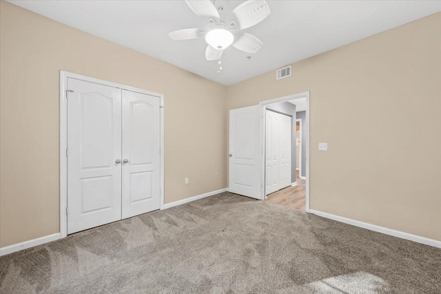 unfurnished bedroom featuring a closet, light colored carpet, and ceiling fan