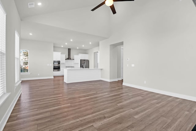 unfurnished living room featuring ceiling fan, high vaulted ceiling, and wood-type flooring