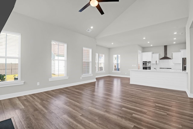 unfurnished living room featuring ceiling fan, dark hardwood / wood-style flooring, and high vaulted ceiling