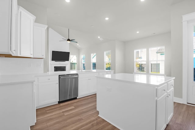 kitchen featuring a center island, white cabinets, stainless steel dishwasher, light hardwood / wood-style floors, and kitchen peninsula