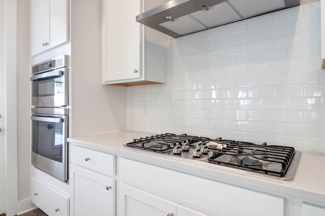 kitchen featuring backsplash, white cabinetry, extractor fan, and appliances with stainless steel finishes