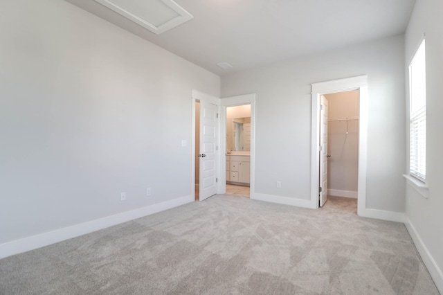 unfurnished bedroom featuring a spacious closet, a closet, and light colored carpet