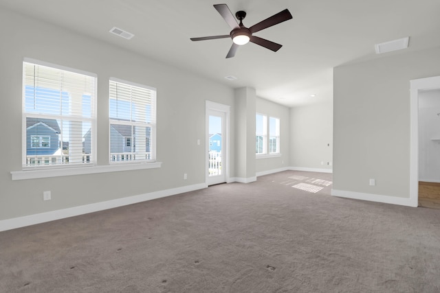 empty room featuring ceiling fan, carpet floors, and a healthy amount of sunlight