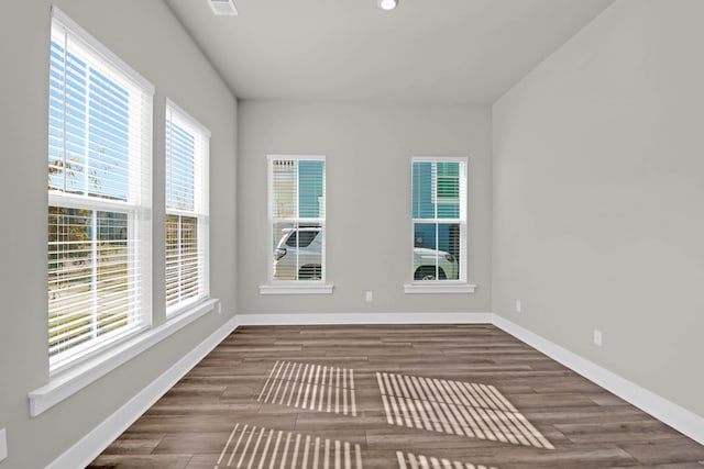 unfurnished room with plenty of natural light and dark wood-type flooring