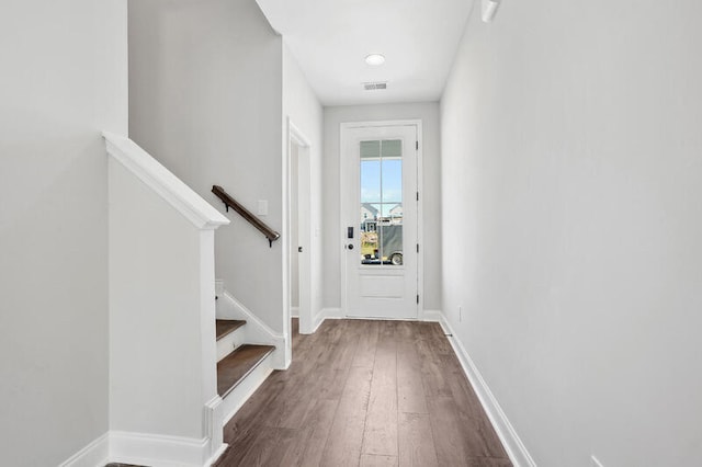 doorway featuring dark wood-type flooring, visible vents, baseboards, and stairs