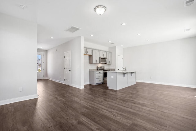 kitchen with dark wood-style floors, visible vents, appliances with stainless steel finishes, open floor plan, and a kitchen island with sink