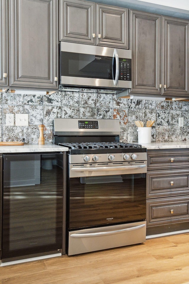 kitchen featuring light wood-type flooring, appliances with stainless steel finishes, and tasteful backsplash