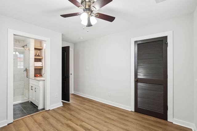 unfurnished bedroom with ensuite bathroom, a closet, ceiling fan, and light wood-type flooring